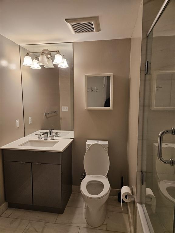 bathroom featuring a shower stall, vanity, toilet, and baseboards