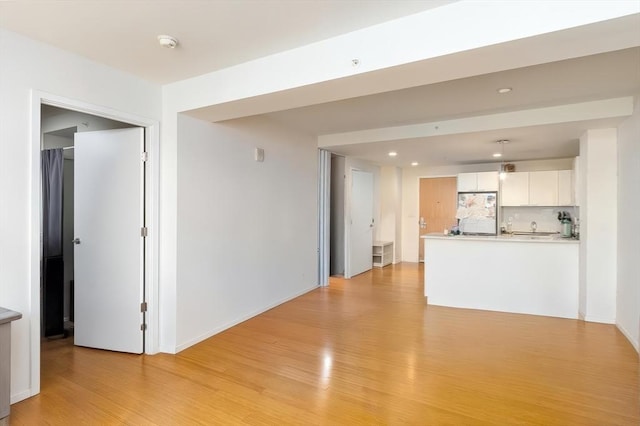 unfurnished living room featuring light wood finished floors, recessed lighting, and baseboards