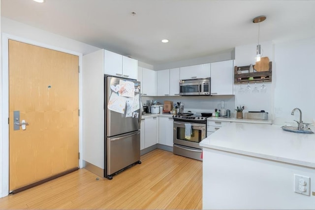kitchen featuring stainless steel appliances, light wood-style floors, light countertops, decorative light fixtures, and recessed lighting