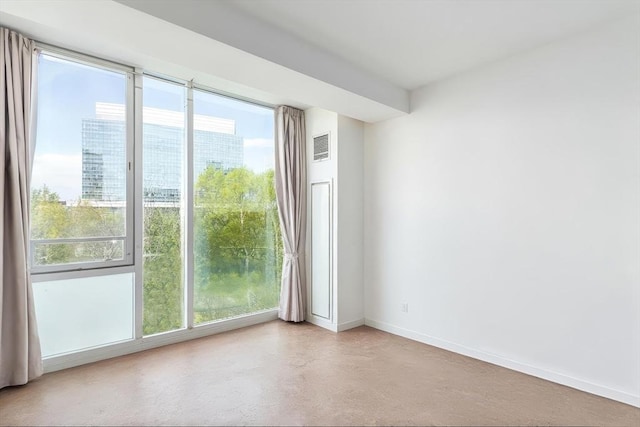 empty room featuring healthy amount of natural light, baseboards, and finished concrete floors