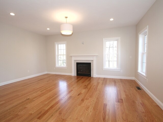 unfurnished living room with light wood-type flooring and a wealth of natural light