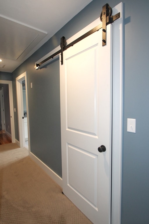 hallway featuring a barn door and carpet flooring