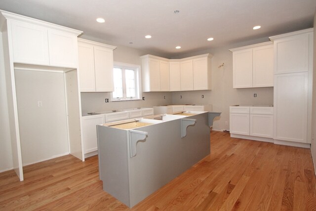 kitchen with light hardwood / wood-style floors, white cabinets, and a kitchen island