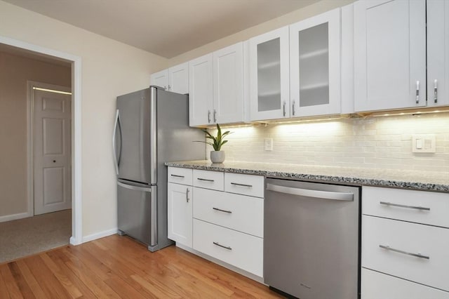 131 Coolidge Ave Unit 422, Watertown, MA 02472 - kitchen featuring appliances with stainless steel finishes, light stone counters, light wood-style floors, white cabinetry, and decorative backsplash