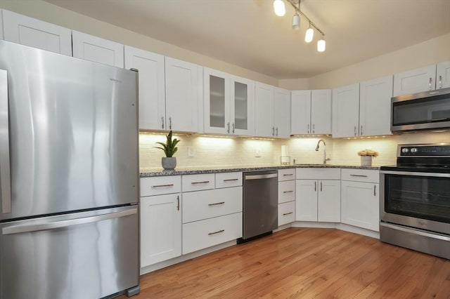 131 Coolidge Ave Unit 422, Watertown, MA 02472 - kitchen with light wood-style floors, tasteful backsplash, light stone counters, a sink, and appliances with stainless steel finishes