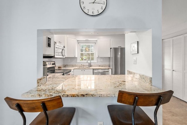 kitchen featuring a sink, backsplash, stainless steel appliances, and a peninsula