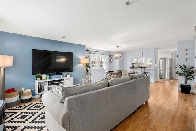 living room with a chandelier, visible vents, and wood finished floors