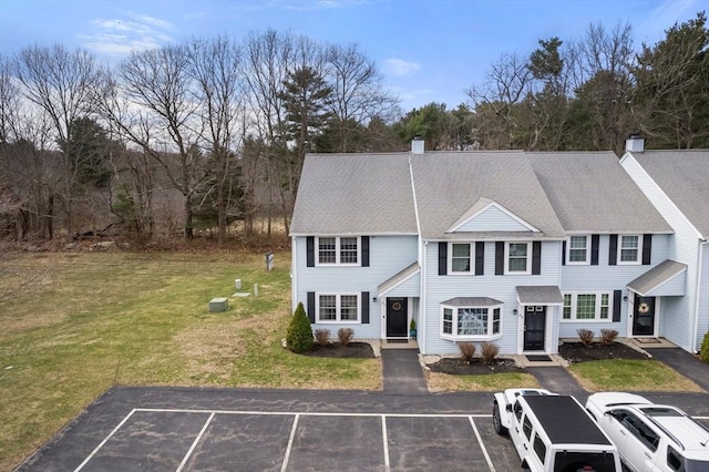 multi unit property featuring uncovered parking, a front lawn, and a chimney