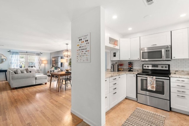 kitchen with appliances with stainless steel finishes, decorative backsplash, open floor plan, and white cabinets