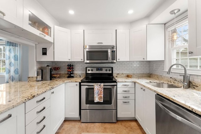 kitchen featuring white cabinets, stainless steel appliances, decorative backsplash, and a sink