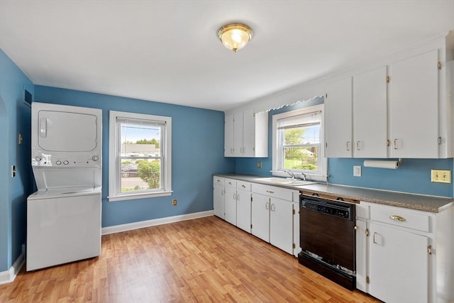 16 Elm St, Leominster, MA 01453 - kitchen featuring dishwasher, stacked washing machine and dryer, white cabinetry, light wood-style floors, and baseboards