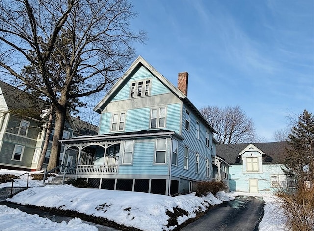 view of front of house with driveway, a chimney, and a porch