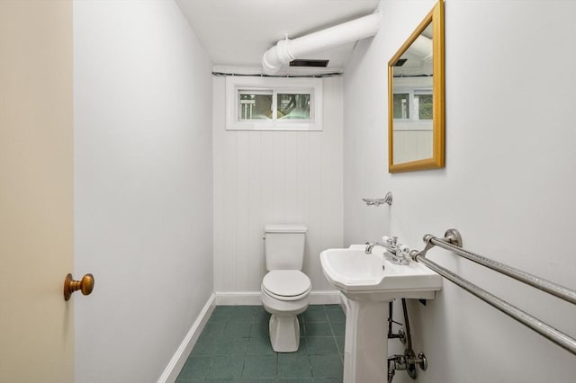 half bath with toilet, baseboards, and tile patterned flooring
