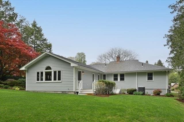 rear view of house featuring a lawn and a chimney