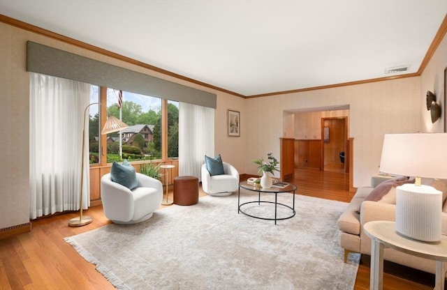 living room featuring wood finished floors, ornamental molding, baseboards, and wallpapered walls