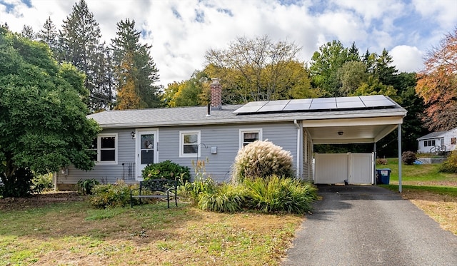 view of front of home with solar panels, a front lawn, and a carport