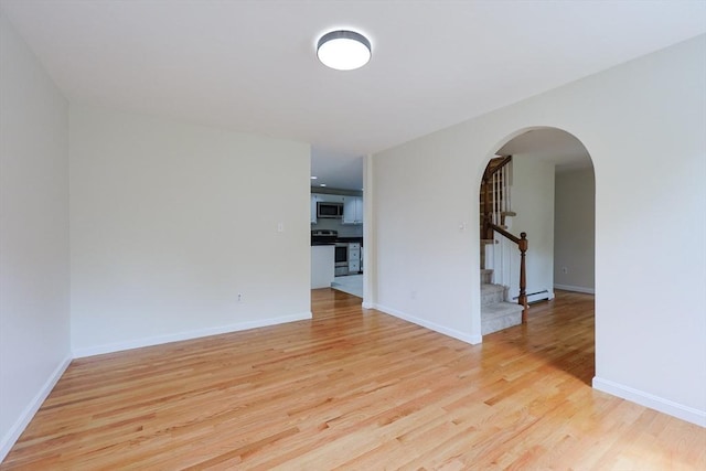 37 Annetta Rd, Ashland, MA 01721 - spare room with arched walkways, a baseboard heating unit, stairs, light wood-type flooring, and baseboards