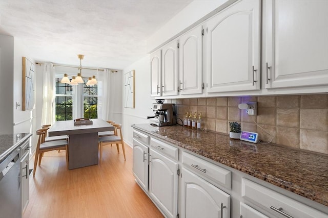 kitchen with stainless steel dishwasher, decorative light fixtures, white cabinetry, and light hardwood / wood-style flooring