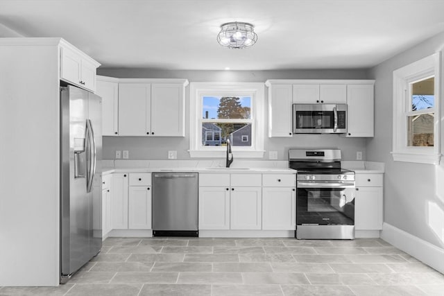 kitchen with stainless steel appliances, a sink, light countertops, and white cabinets