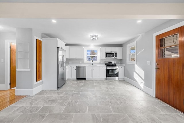 kitchen featuring stainless steel appliances, light countertops, baseboards, white cabinetry, and recessed lighting