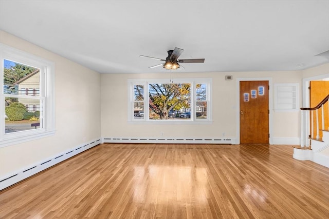 unfurnished living room with light wood finished floors, stairway, plenty of natural light, and baseboards