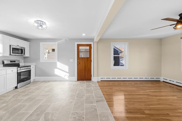 kitchen featuring appliances with stainless steel finishes, ceiling fan, a baseboard heating unit, baseboards, and white cabinets