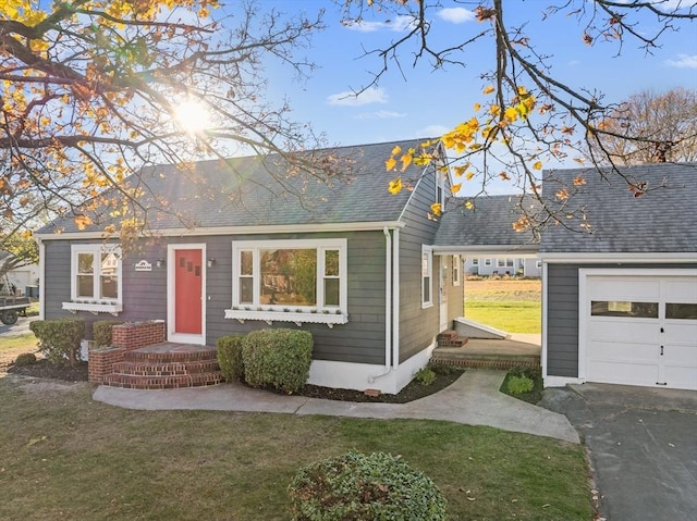 view of front of property with a front yard, a garage, roof with shingles, and asphalt driveway