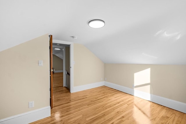 bonus room with light wood-style flooring, vaulted ceiling, and baseboards