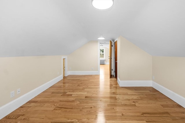 additional living space with light wood-type flooring, baseboards, and lofted ceiling
