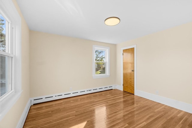 unfurnished room with a baseboard radiator, wood finished floors, and baseboards