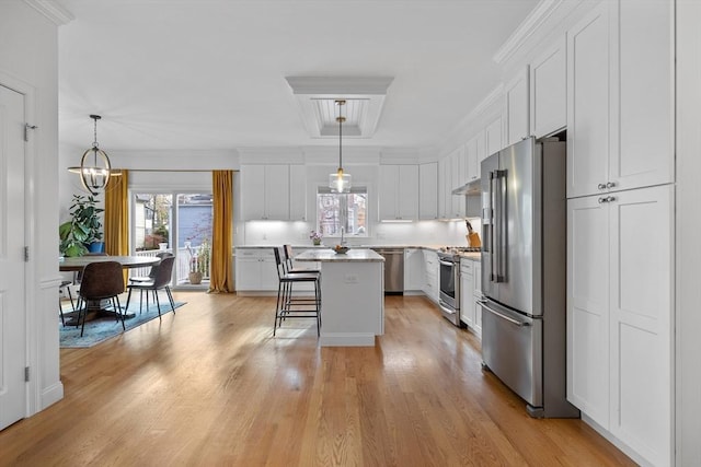 kitchen featuring pendant lighting, appliances with stainless steel finishes, a kitchen breakfast bar, white cabinets, and a kitchen island