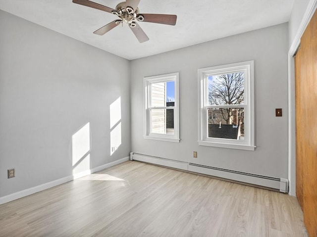 spare room featuring light wood finished floors, baseboards, baseboard heating, and a ceiling fan