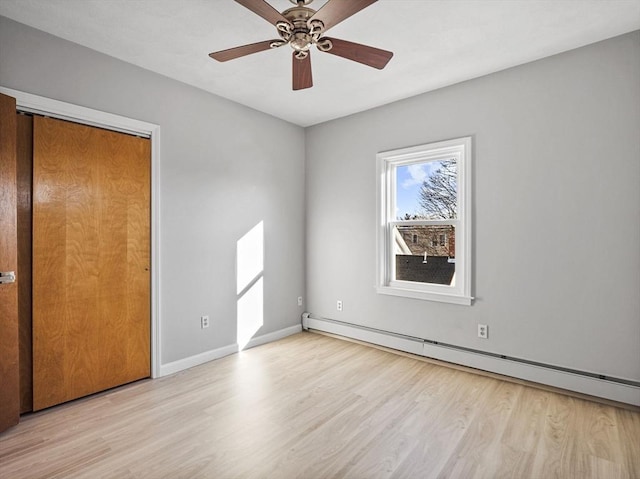 unfurnished bedroom featuring a baseboard radiator, ceiling fan, baseboards, and wood finished floors