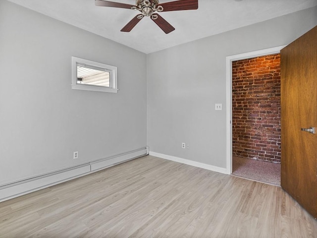 unfurnished room with baseboards, brick wall, ceiling fan, light wood-type flooring, and a baseboard heating unit