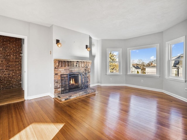 unfurnished living room with wood-type flooring, a fireplace, and baseboards