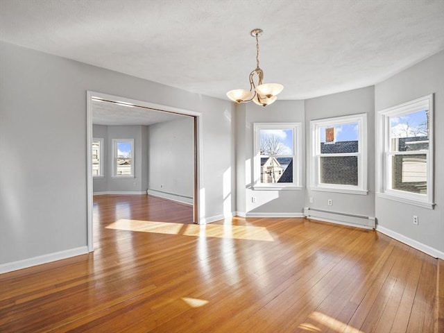 unfurnished dining area featuring a baseboard heating unit, light wood-type flooring, baseboards, and a notable chandelier