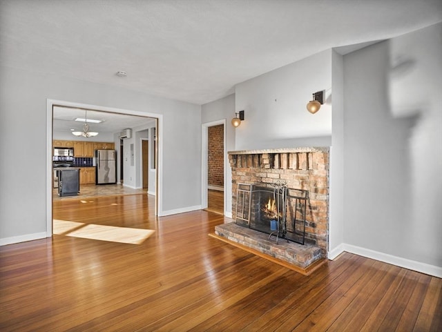 unfurnished living room with hardwood / wood-style floors, a fireplace, and baseboards