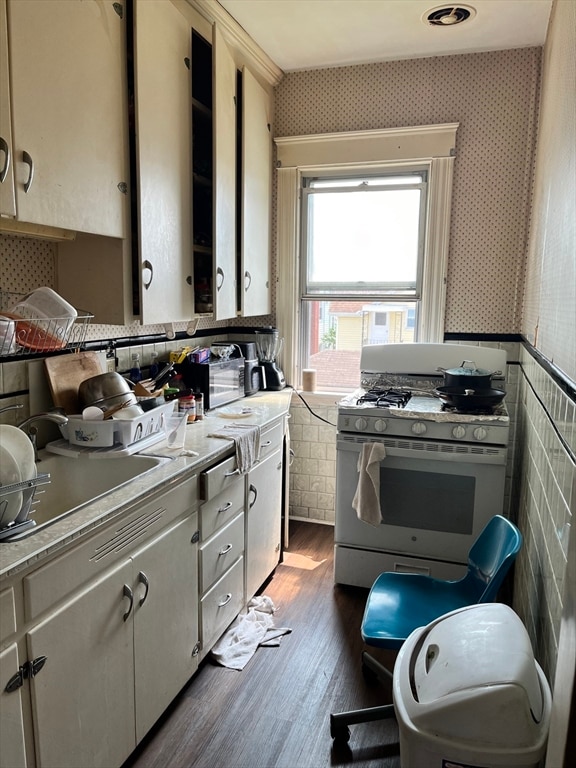 kitchen with dark wood-type flooring, tile walls, and white gas stove