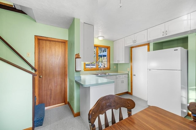 kitchen with white fridge, white cabinetry, and sink