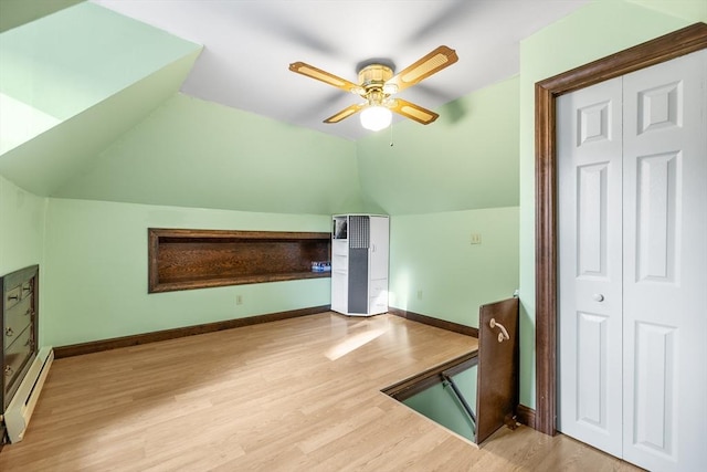 additional living space with ceiling fan, lofted ceiling, light wood-type flooring, and a baseboard radiator