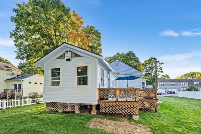 back of property with a deck and a yard