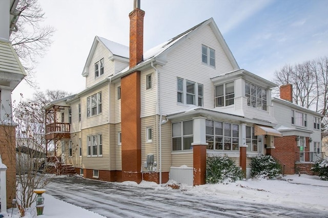 snow covered back of property with a sunroom