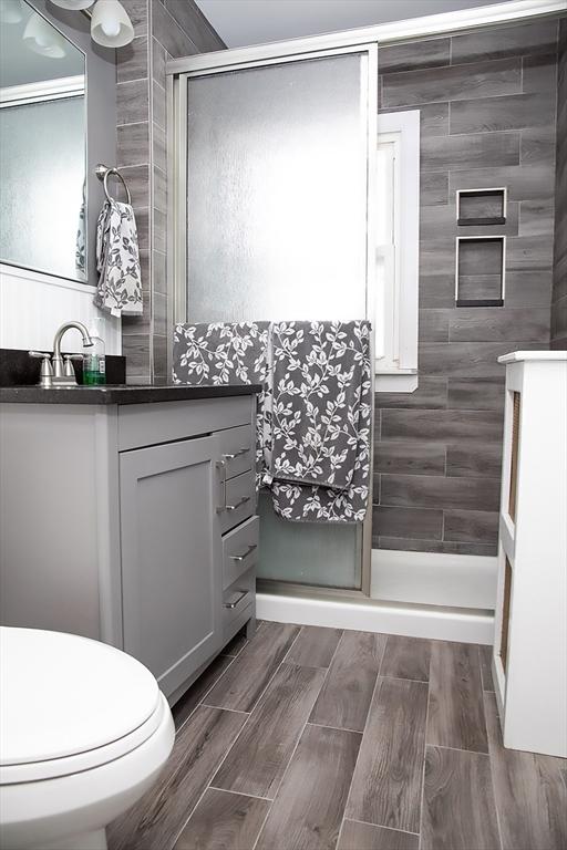 bathroom featuring vanity, a shower with shower door, and toilet