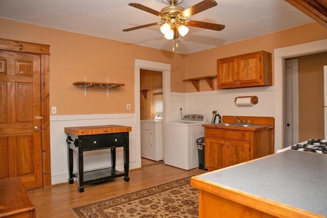 kitchen featuring sink, ceiling fan, washer and clothes dryer, and light hardwood / wood-style flooring