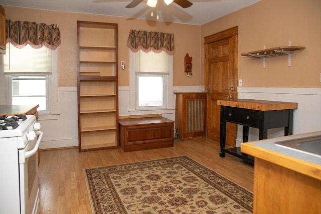 kitchen with light wood-type flooring, ceiling fan, and white gas stove