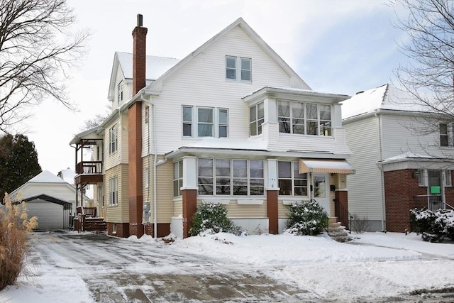 view of front facade with an outbuilding, a garage, and a sunroom