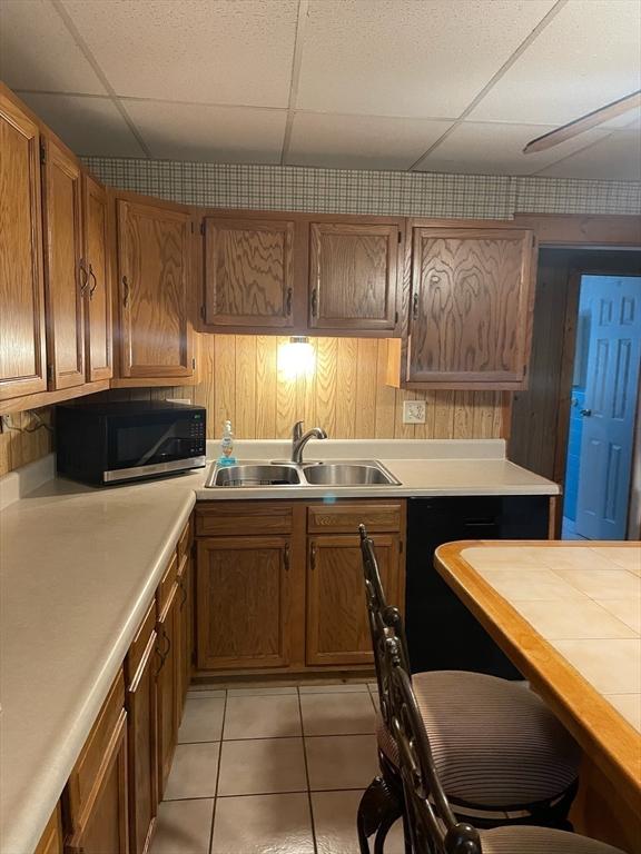 kitchen featuring sink, light tile patterned floors, and a drop ceiling