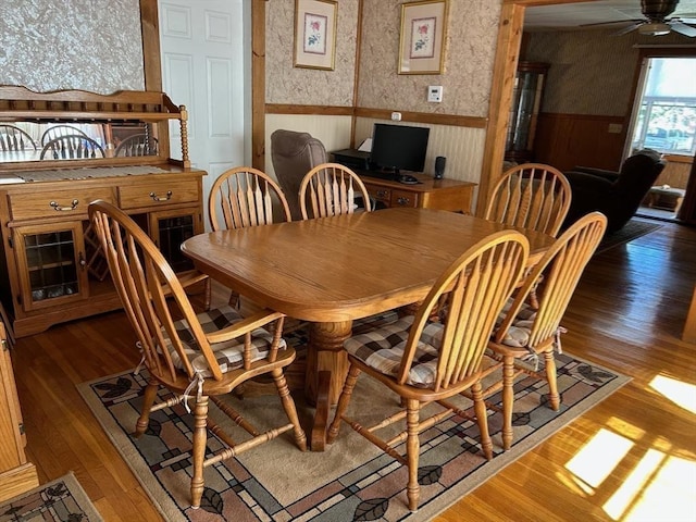 dining area featuring ceiling fan, wooden walls, and dark wood-type flooring