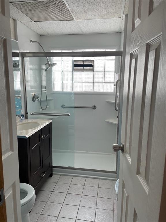 bathroom featuring vanity, toilet, a shower with shower door, and tile patterned flooring