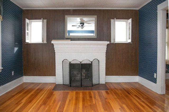 unfurnished living room with a fireplace, wood-type flooring, crown molding, and a healthy amount of sunlight